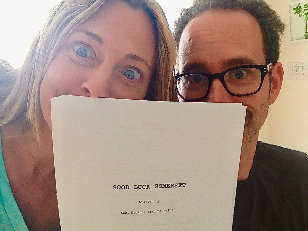 Kasi Brown and Brandon Walter peeking over a script